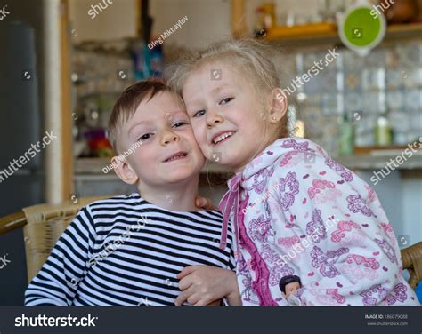 cute little brother and sister posing together sitting with their cheeks touching smiling at the
