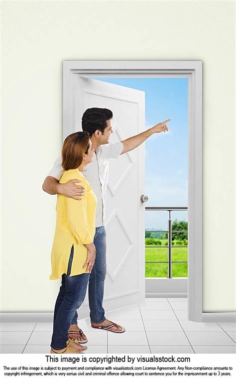 indian couple standing entrance door  pointing showing  home