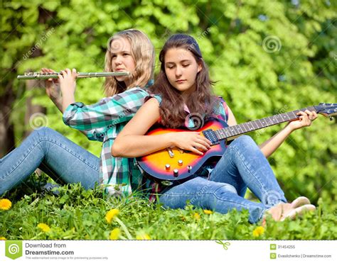 Two Girls Playing Guitar And Flute In The Park Royalty