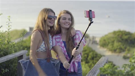 Cute Teen Girls Take Fun Selfies Together At Beach Stock