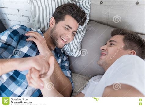 Overjoyed Gay Couple Holding Each Others Hand In Bed Stock Image