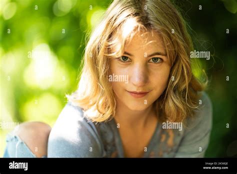 22 yo blonde woman close up with a natural green bokeh background