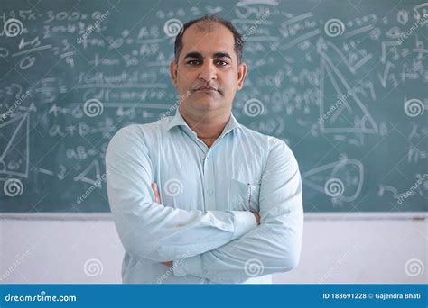 Portrait Of Serious Male Teacher Standing Against Blackboard Teaching