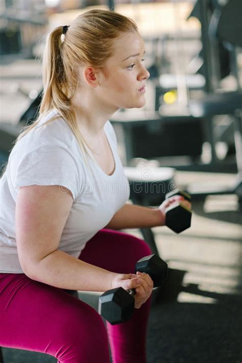 beginner chubby girl exercising in fitness club stock