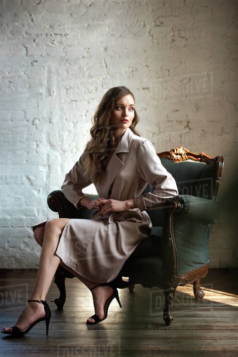 Elegant Woman In Classic Trench Coat Posing In Armchair