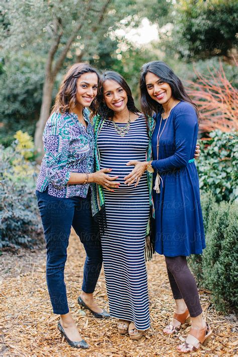 beautiful sisters touching the pregnant belly of their little sister