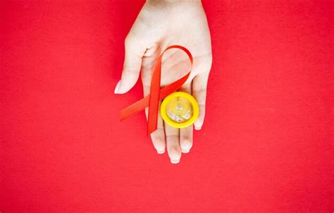 Premium Photo Close Up Of Womans Hands Holding Red Ribbon And Condom