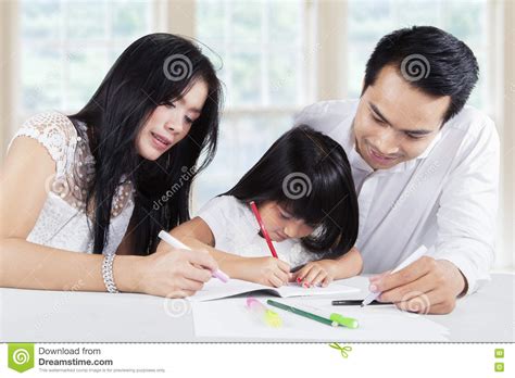 dad and mom help their daughter doing homework stock image