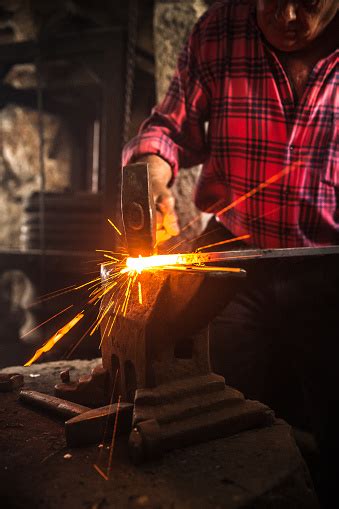 senior blacksmith man forging an iron craft on anvil stock