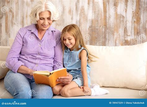 kind granny and girl entertaining with book at home stock image image