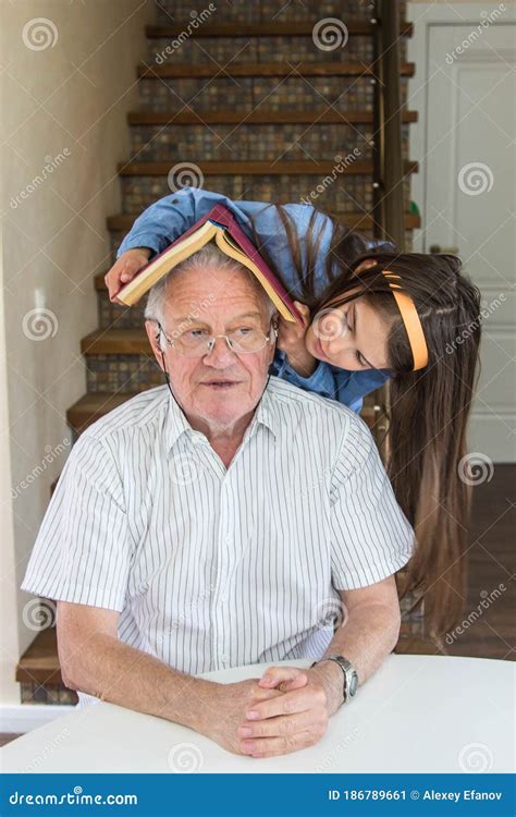 Grandfather And Granddaughter Sit At The Table And Play Stock Image