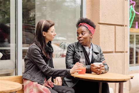 Young Lesbian Couple Interacting By Table In Outdoor Cafe Stock Image