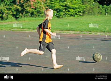 young boy playing football   bare feet stock photo  alamy