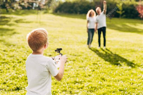 chico jugando  drone mientras padres de pie detras en park