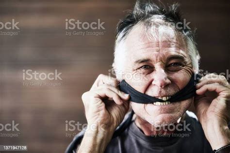 man gagged with a strip of black cloth takes it off symbolizing freedom