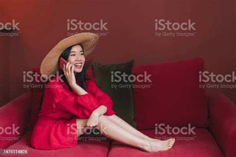 Wanita Cantik Asia Berbaju Merah Dengan Topi Jerami Duduk Di Sofa Merah