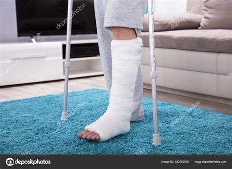 man broken leg  crutches walking blue carpet stock photo  candreypopov
