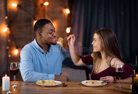 Romantic Interracial Couple Having Dinner Date In Restaurant Feeding