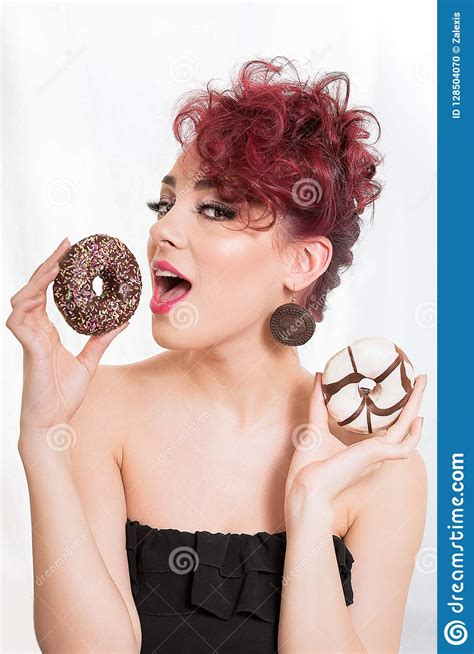 beautiful redhead woman holding two glazed donuts in her