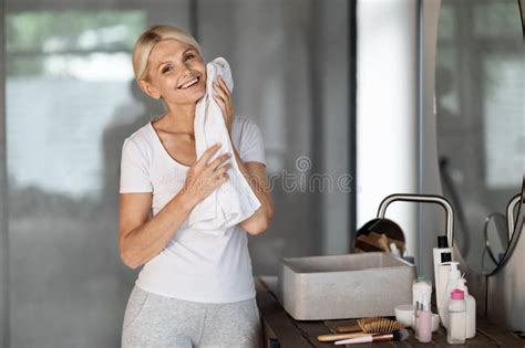 Mature Woman Applying Hair Repair Serum While Standing Near Mirror In