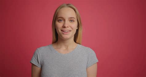 blonde girl being funny and puffing out her cheeks at pink wall