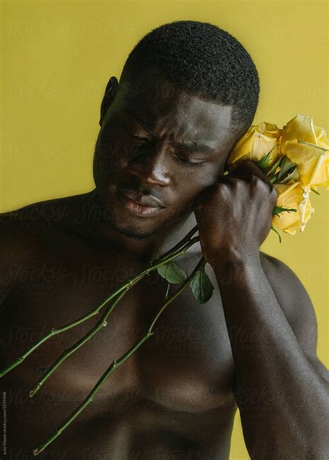 portrait of a handsome fit african guy holding yellow roses near his