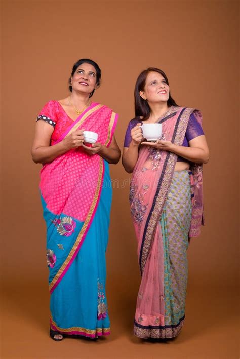 two mature indian women holding coffee or tea cup stock image image