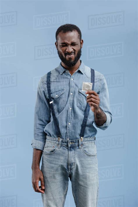 grimacing african american man holding condom isolated on
