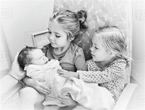 portrait   sisters holding newborn baby brother vancouver