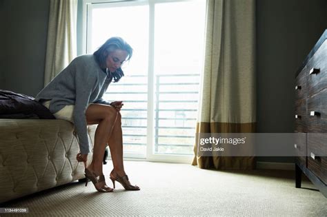 mature woman sitting on bed putting on high heels photo getty images
