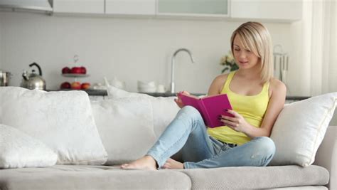 Cute Girl Relaxing On Sofa Reading Book Closing It And Smiling At