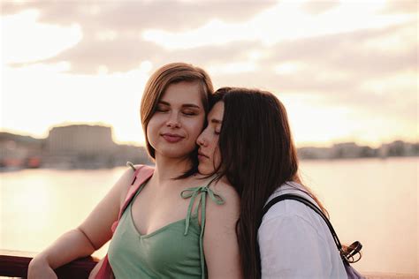 portrait of happy lesbian couple standing on bridge at sunset