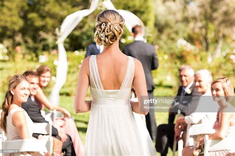 bride walking down the aisle during wedding ceremony high res stock