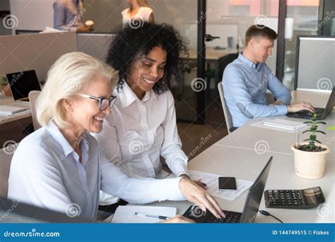 Smiling Old Mentor Helping African Intern With Laptop In Office Stock