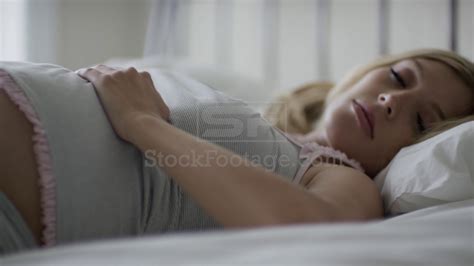 Close Up Slow Motion Panning Shot Of Pregnant Woman Sleeping On Bed
