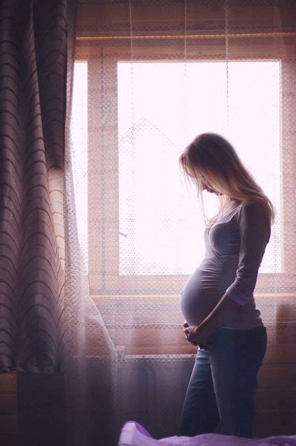 A Pregnant Woman Standing In Front Of A Window