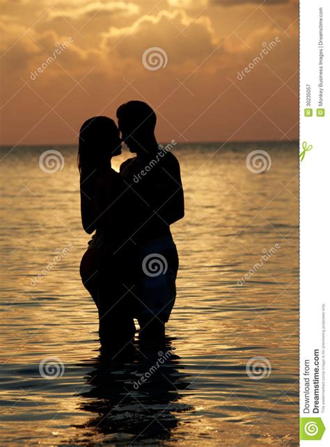 Silhouette Of Romantic Couple Standing In Sea Royalty Free