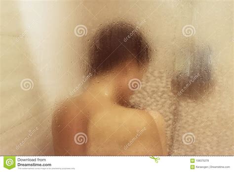 beautiful woman in the shower behind glass with drops