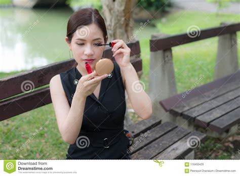 beautiful asian woman applying black mascara on eyelashes