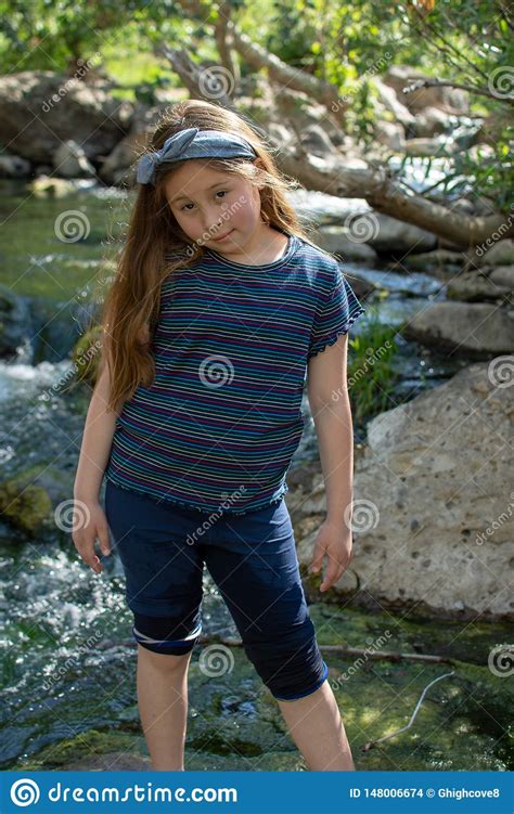 little latina girl smiling coyly and looking down while standing in