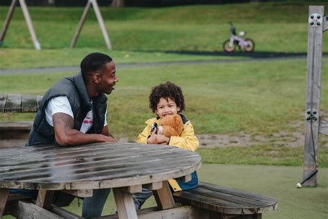 joyeux père et fils noirs assis à table dans le parc · photo gratuite