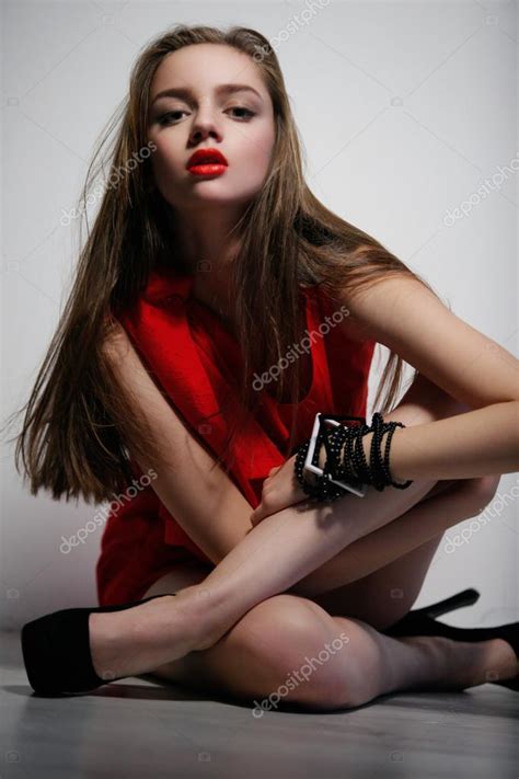 Woman In Red Dress Sitting On Floor With Crossed Legs