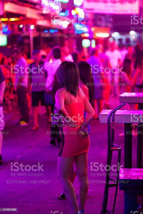 two pretty thai bar girls in dress are standing in red light street