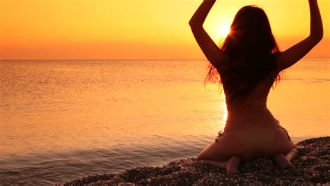 silhouette of a woman sitting on a beach at sunset stock footage video