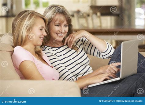 Mãe Com A Filha Adolescente Que Senta Se Em Sofa At Home Using Laptop