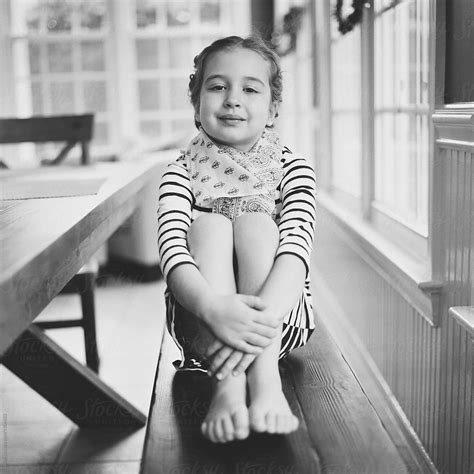 Cute Young Girl Holding Her Legs Sitting On A Bench By Stocksy