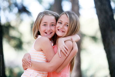 twin sisters hugging each other outdoors by stocksy contributor dina