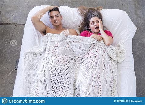 Funny Married Couple Lying In Bed And Hiding Under White Blanket Stock