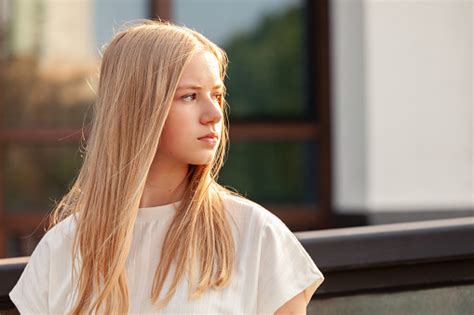 outdoors portrait of 15 year old blonde teen girl with long hair in