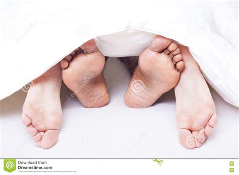 black and white feet of interracial couple in bed stock